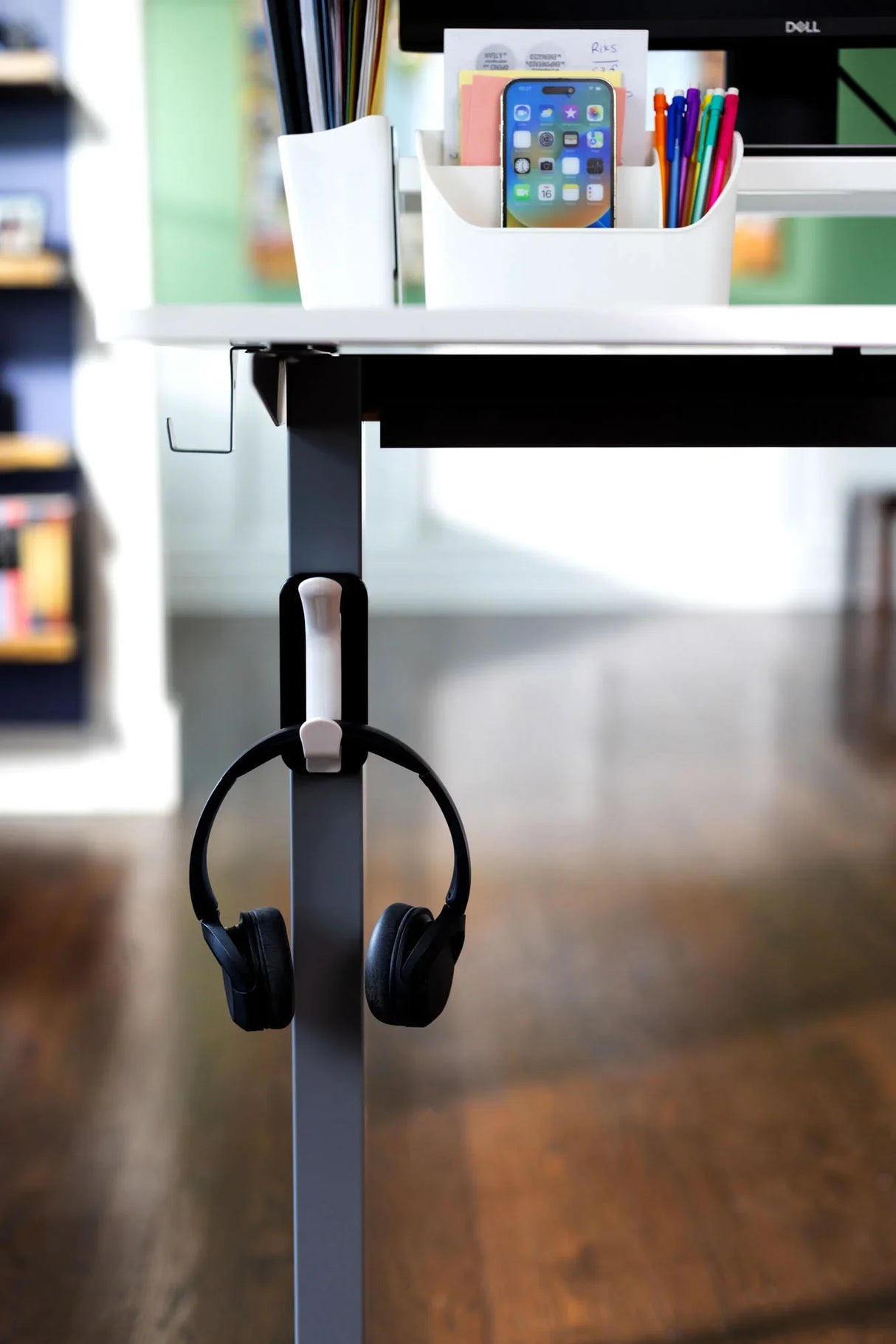 Modern desk with organizer, pens, phone holder, and headphones on a desk hook