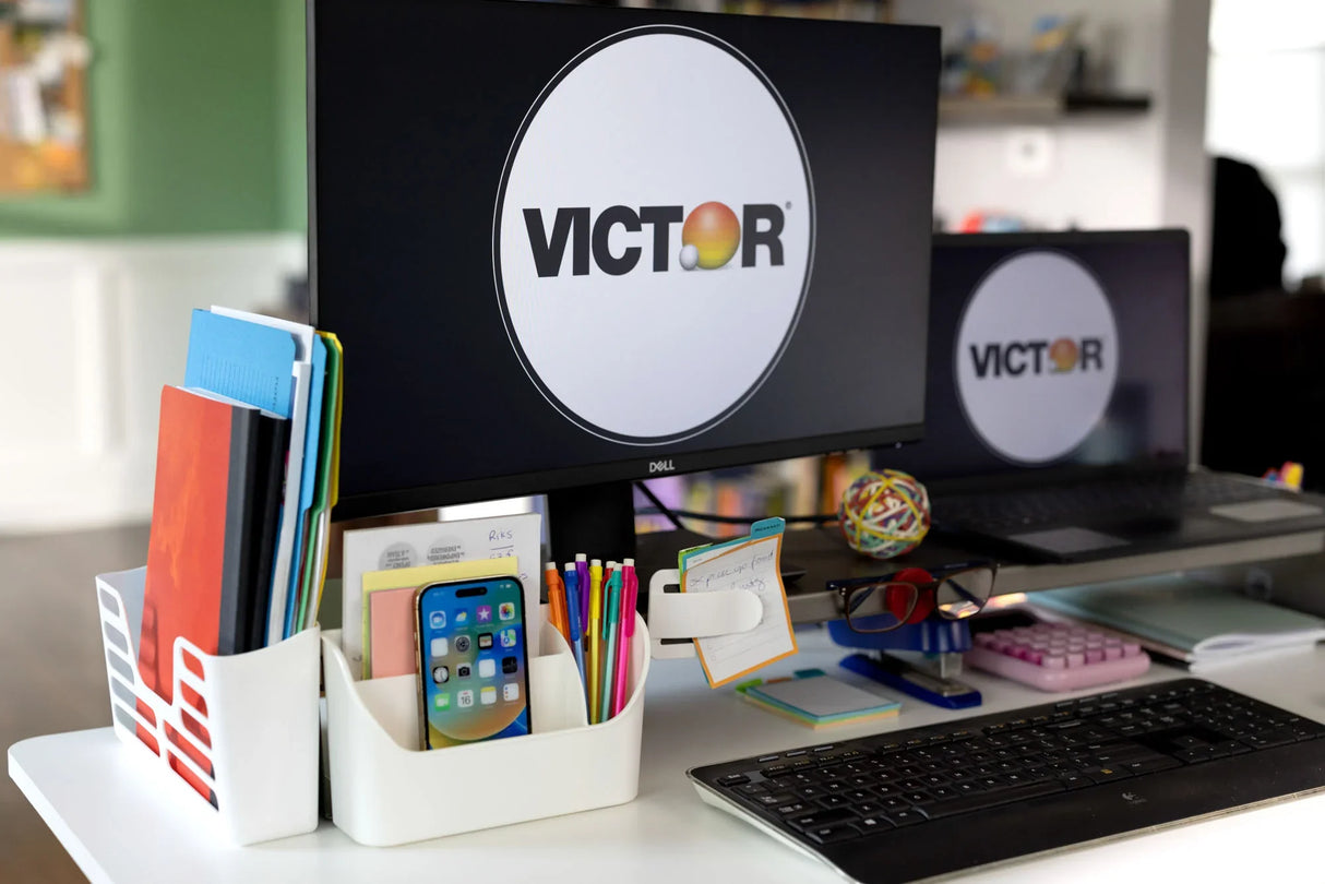 Modern office desk setup with dual monitors, document holder, pens, smartphone, and keyboard