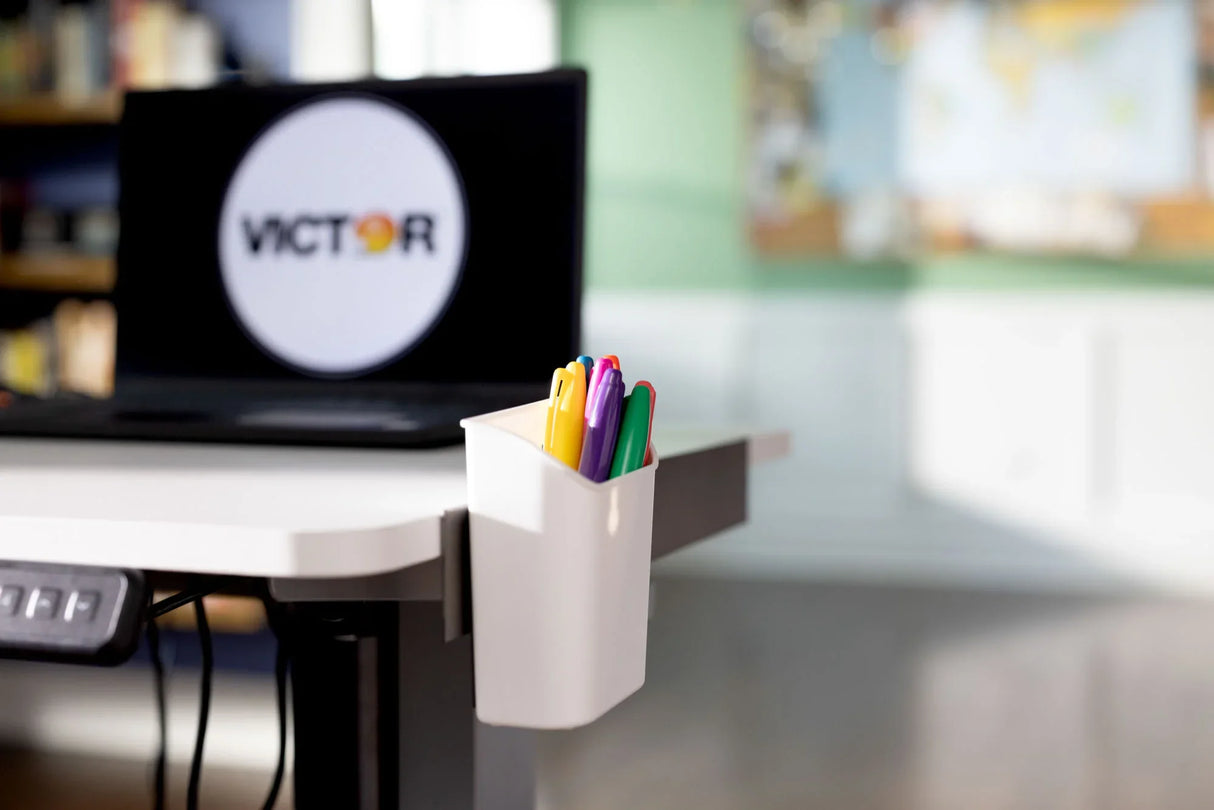 White desk organizer holding colorful pens attached to standing desk in office setting