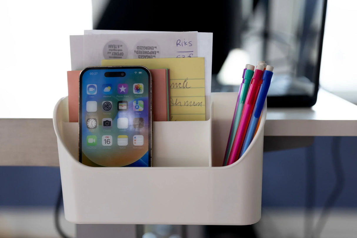 Desk organizer with phone, pens, sticky notes, and papers on an office desk