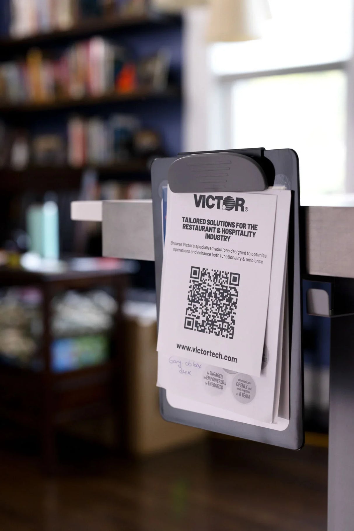 Gray desktop document holder with Victor-branded paper and QR code, home office background