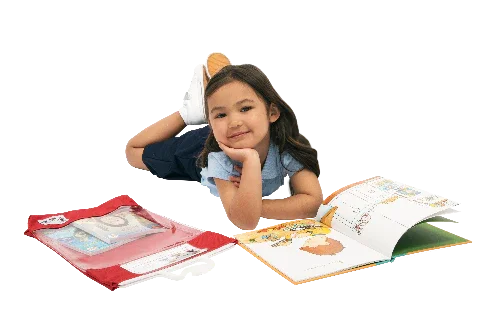 Child reading a book while lying beside a transparent red book bag and an open picture book