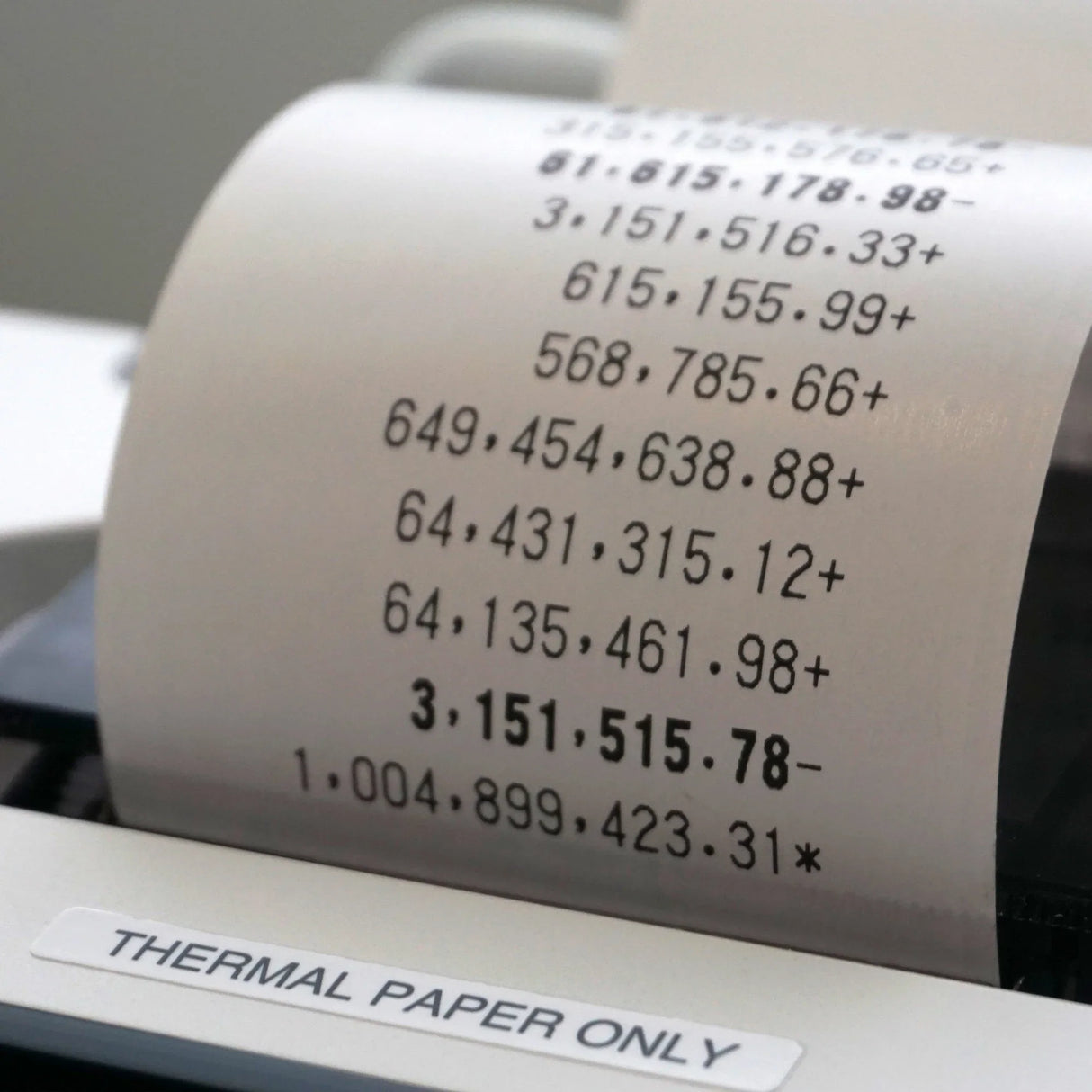 Closeup of a thermal print calculator with 12-digit display printing calculations on paper roll