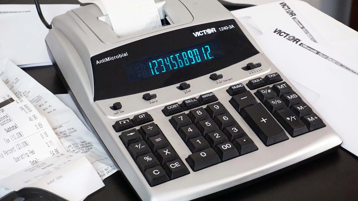 Victor® 12-digit heavy-duty commercial printing calculator with blue digital display and paper rolls.
