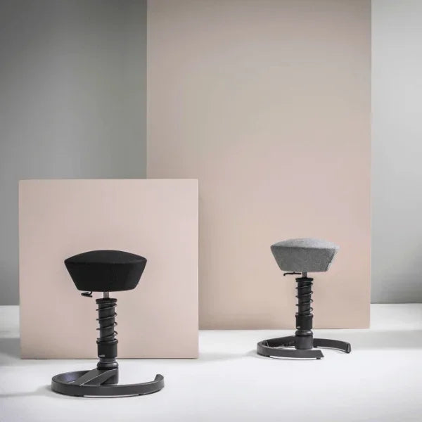 Two Aeris Swopper Ergonomic Office Stools in black and grey against a neutral background.