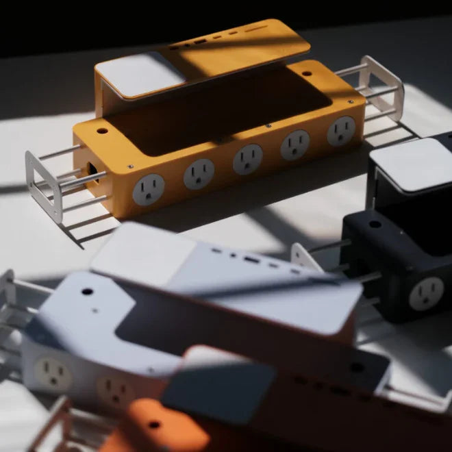 Modern desk power strip organizers with outlet slots in yellow, white, and black, on a table.
