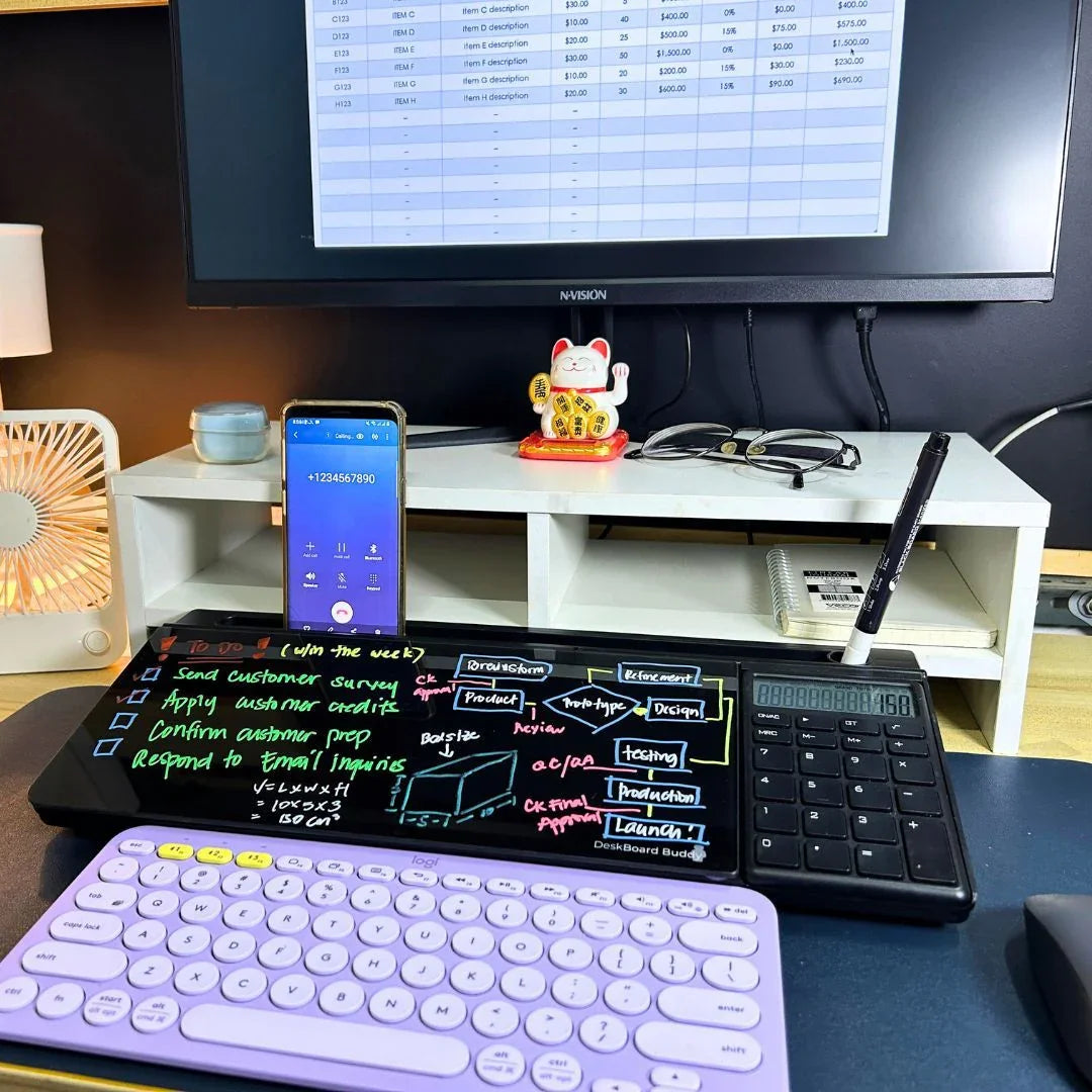 Desktop workspace with digital calculator, glass board organizer, pastel keyboard, and monitor.