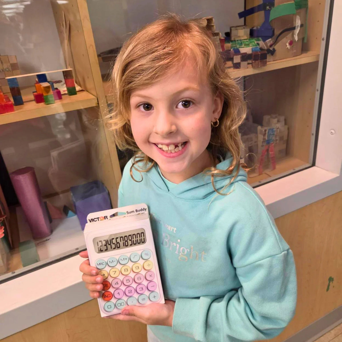 Child holding Victor Sum Buddy calculator with colorful buttons, perfect for school math learning and classroom use.