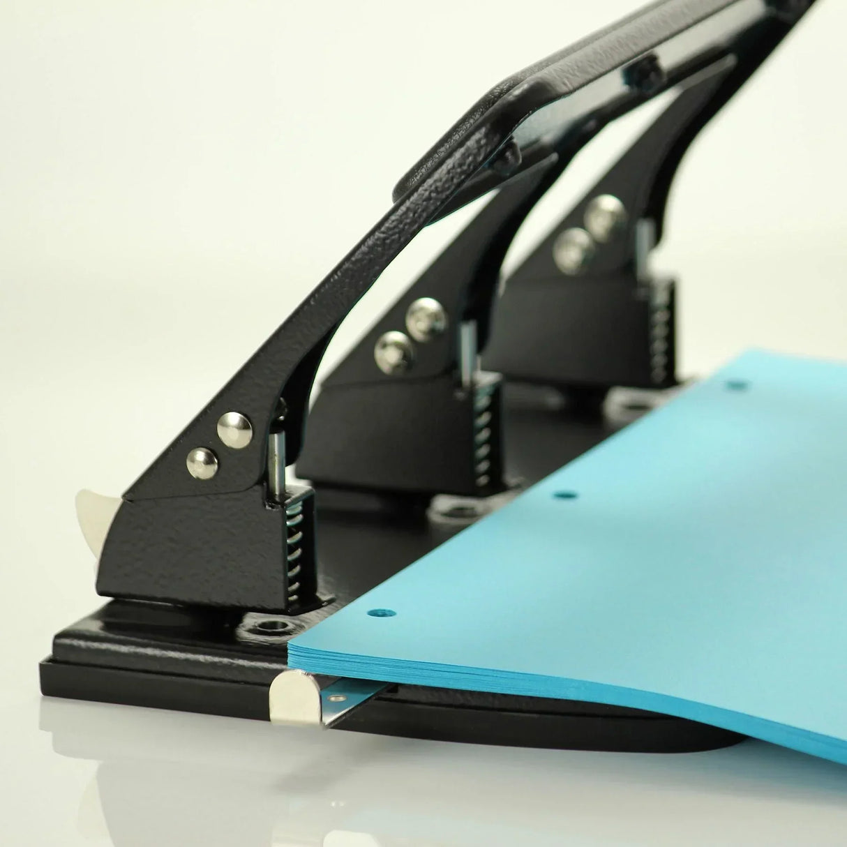 Black heavy-duty hole puncher with blue paper, ideal for office and school organization tasks