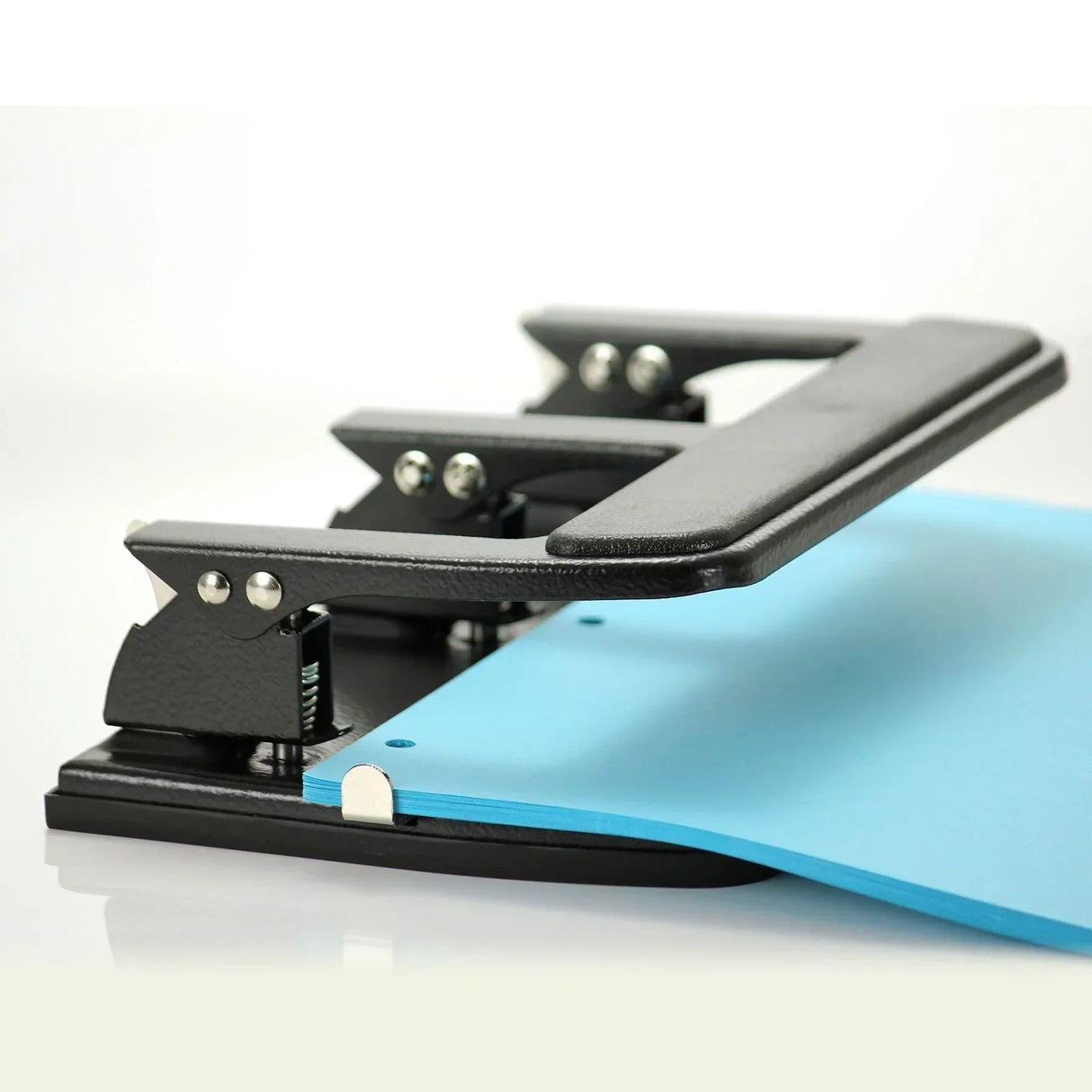Black heavy-duty stapler punching blue paper for office or school use