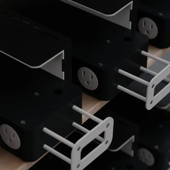Black metal desk organizers with built-in power outlets neatly stacked on a shelf