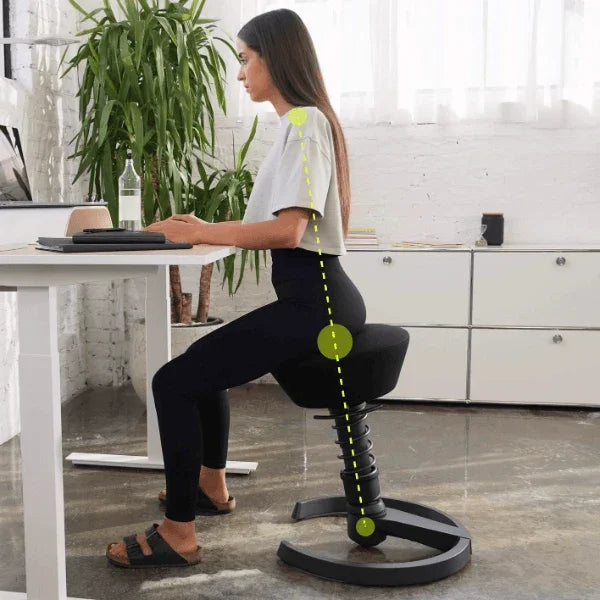 Woman sitting on an Aeris Swopper ergonomic office stool showing aligned posture at a desk.