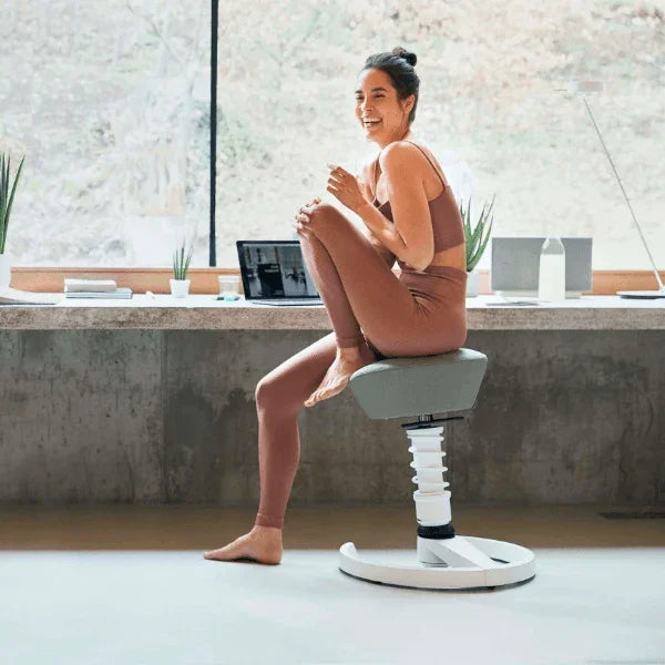 Woman sitting on an Aeris Swopper Ergonomic Office Stool at a modern workspace.