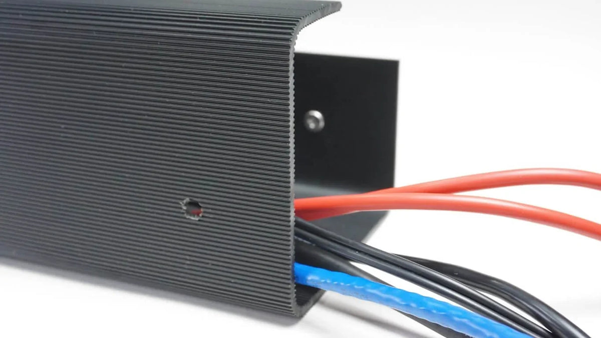 Close-up of red, blue, and black cables organized inside an Officemate Magnetic Cable Tray.