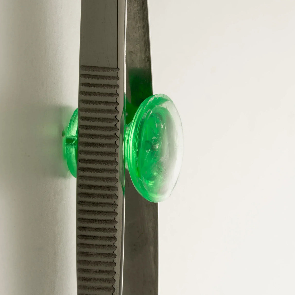 Green suction cup holding metal ruler against white surface for precise measurements