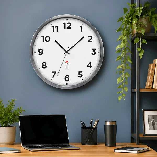 Alba silver grey indoor/outdoor wall clock on a blue wall above a desk with a laptop.