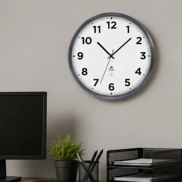 Alba silver grey indoor/outdoor wall clock on a grey wall above a desk with office accessories