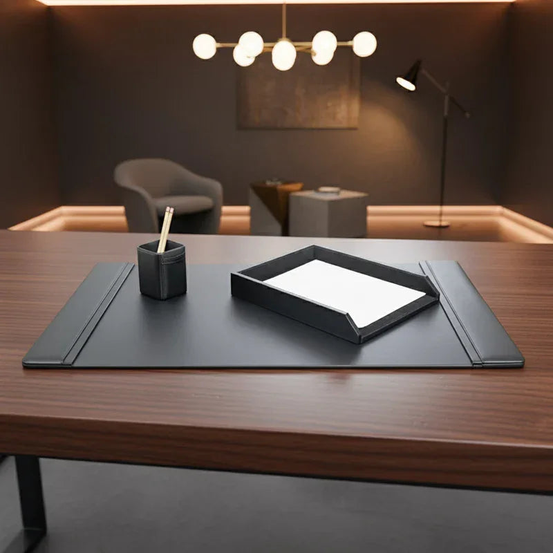 Black leather desk set with pencil holder, paper tray, and desk pad on wooden office desk