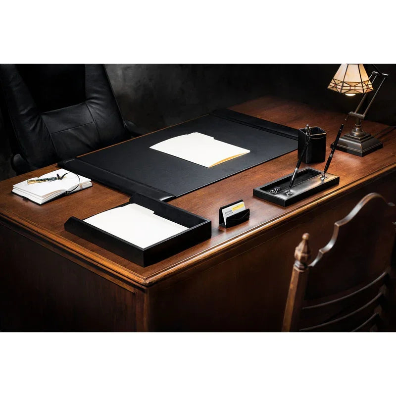 Black leather desk pad with side rails on wooden office desk, organizer sets and lamp