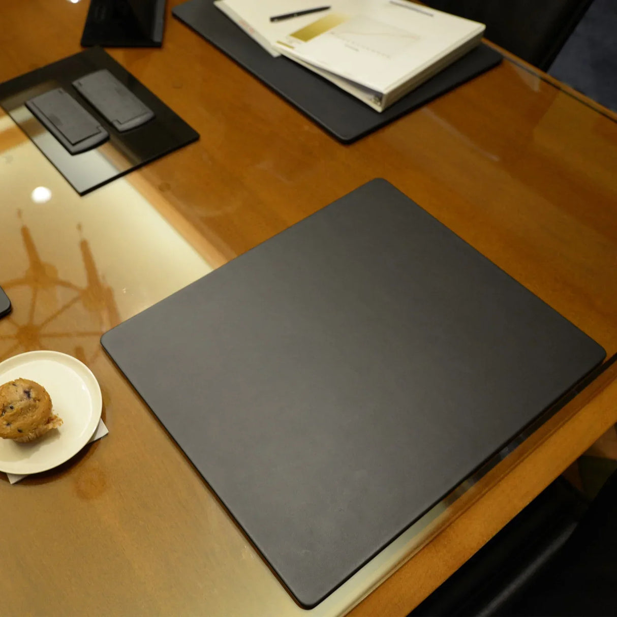 Black leatherette 20 x 16 inch conference table pad on a wood meeting table