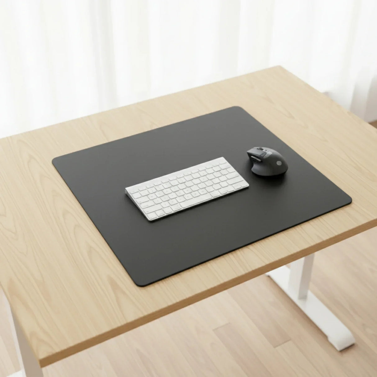 Black leatherette conference table pad on light wood desk with keyboard and mouse