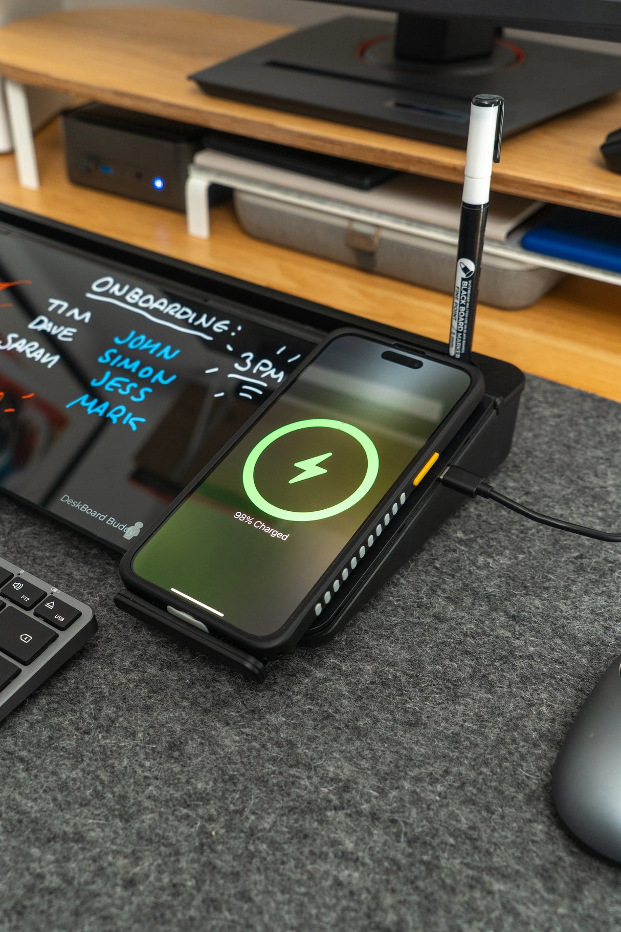 Wireless phone charging on black desk organizer with pen holder and glass memo board in office setup