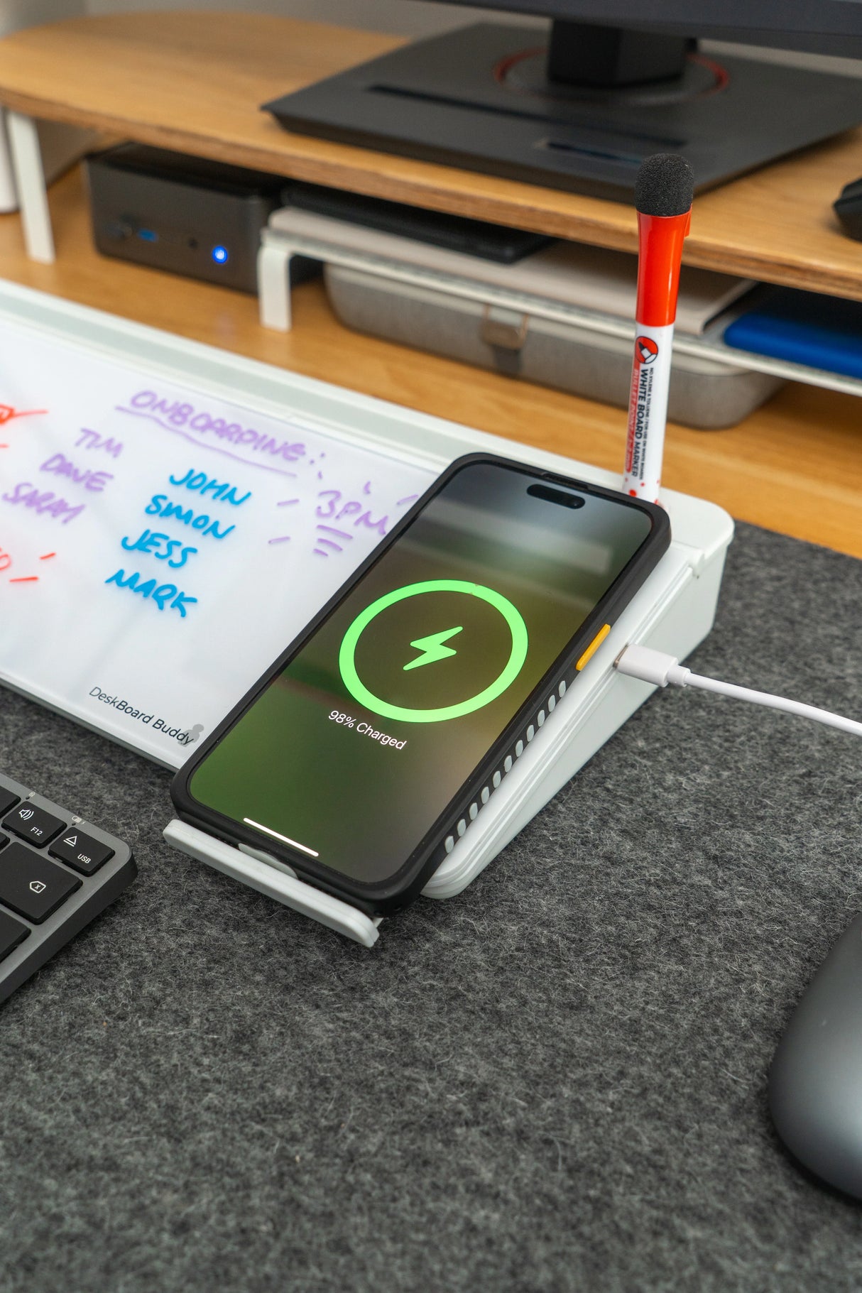 Phone wirelessly charging on desk organizer with whiteboard and marker in modern workspace