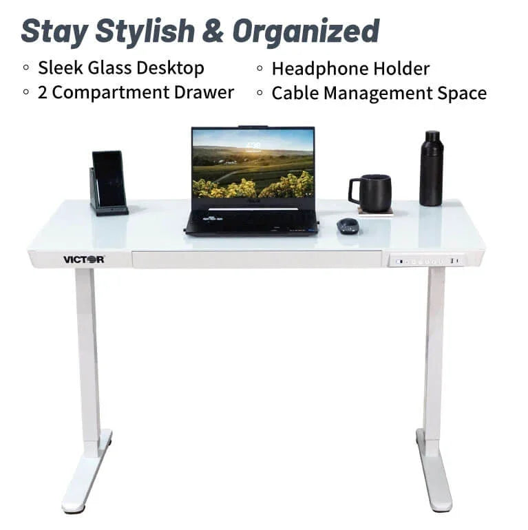 Victor® Electric Glass Topped Standing Desk with laptop, drawer, and cable management.