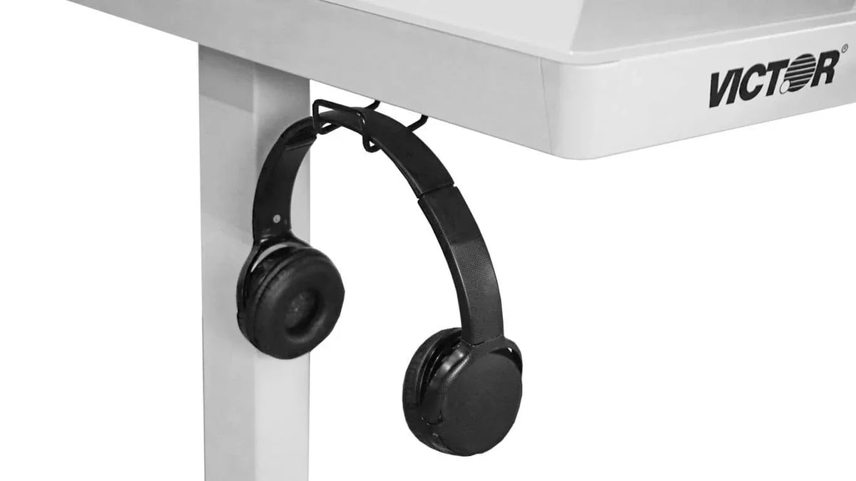 Black headphones hanging from a built-in hook under a Victor® electric standing desk.