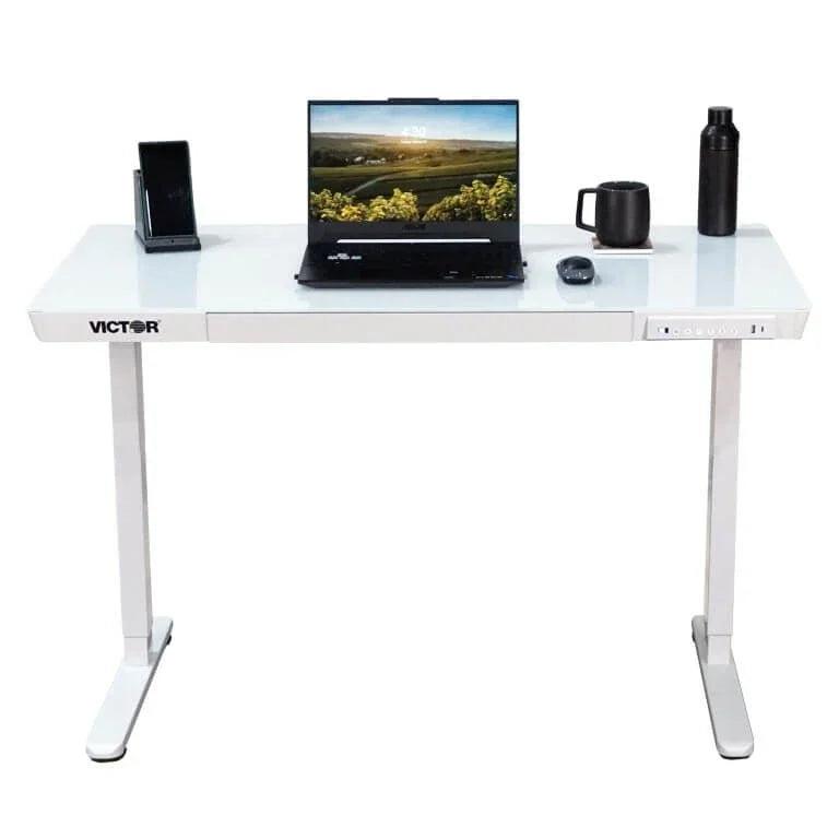 Victor® Electric Glass Topped Standing Desk with a laptop, mouse, and accessories.