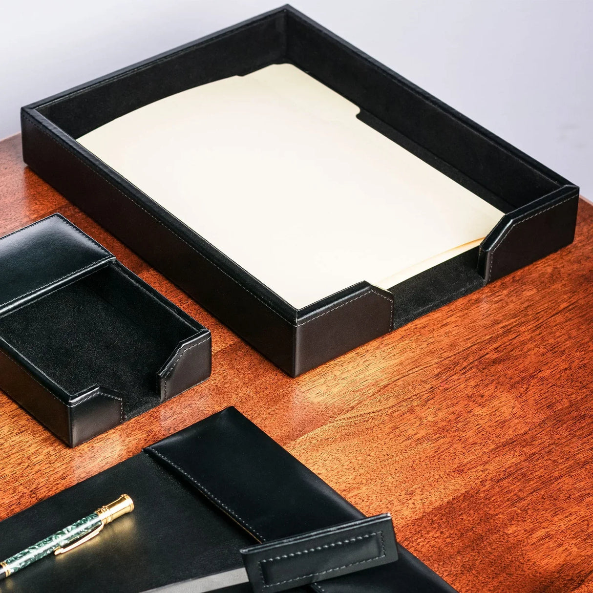 Black leather letter tray with file folders on wooden office desk, desk organizer set