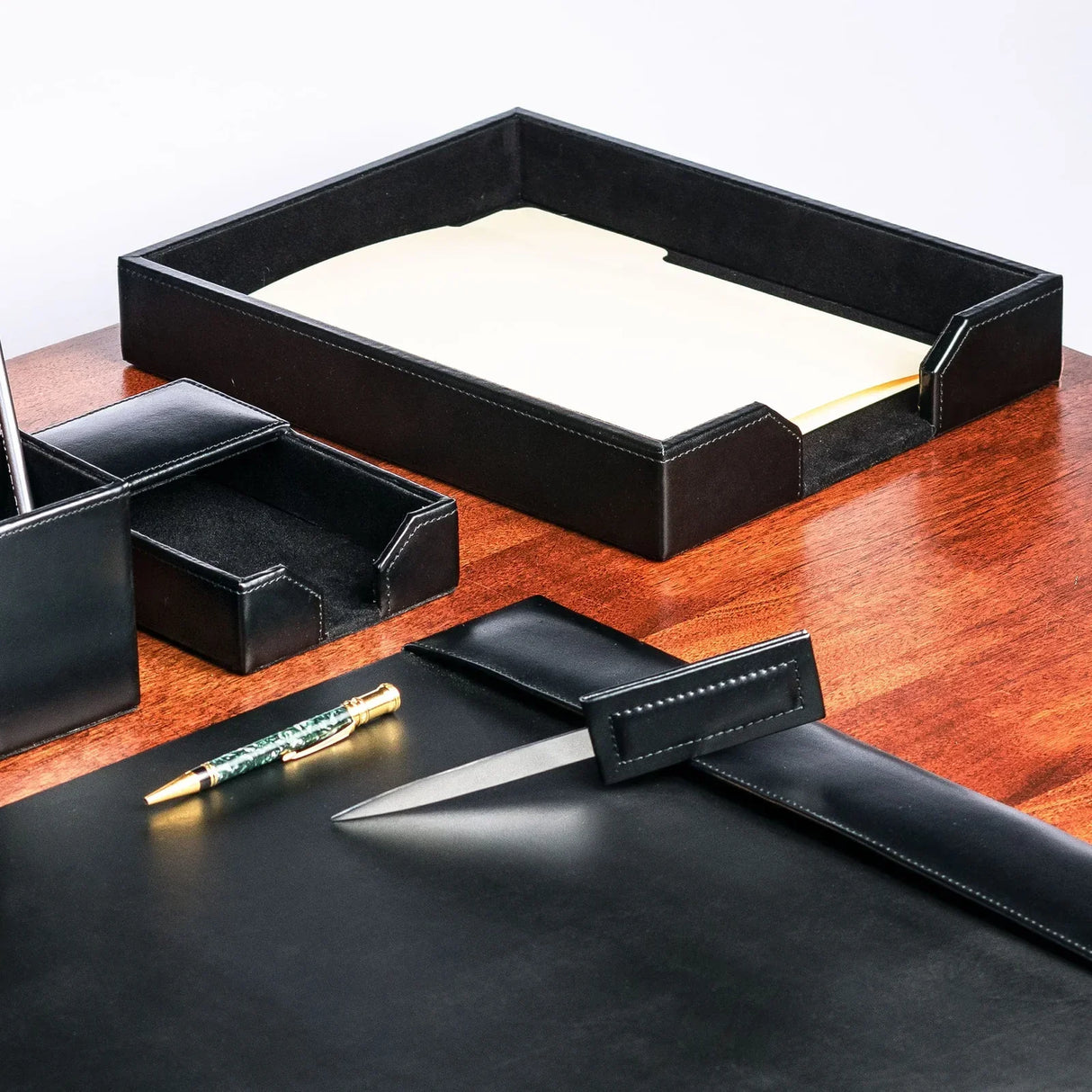 Black leather letter tray with papers, desk organizer set on wooden office desk