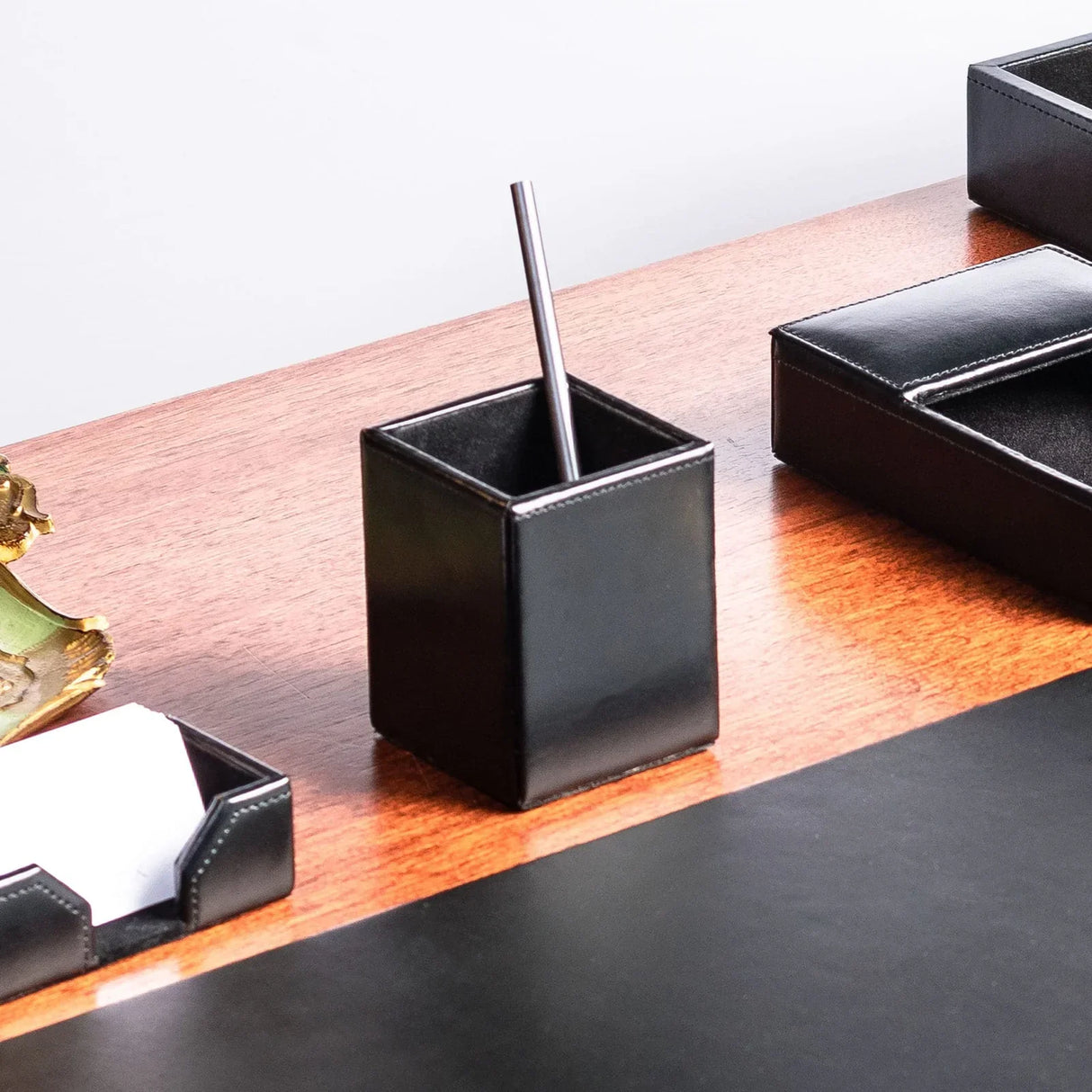 Black leather pencil cup on wooden desk with office organizers
