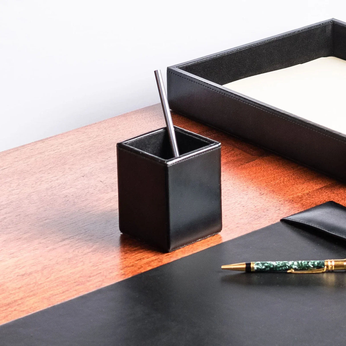 Black bonded leather pencil cup on wooden desk with pen and desk organizer