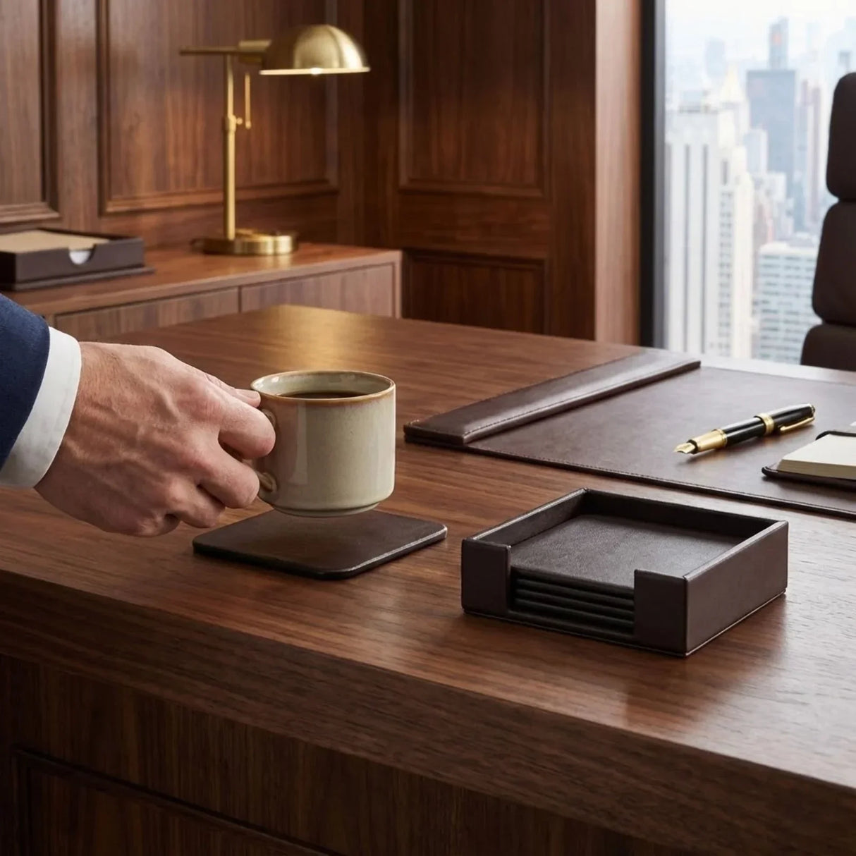 Black leather square coaster set with holder on wooden office desk, mug on coaster.