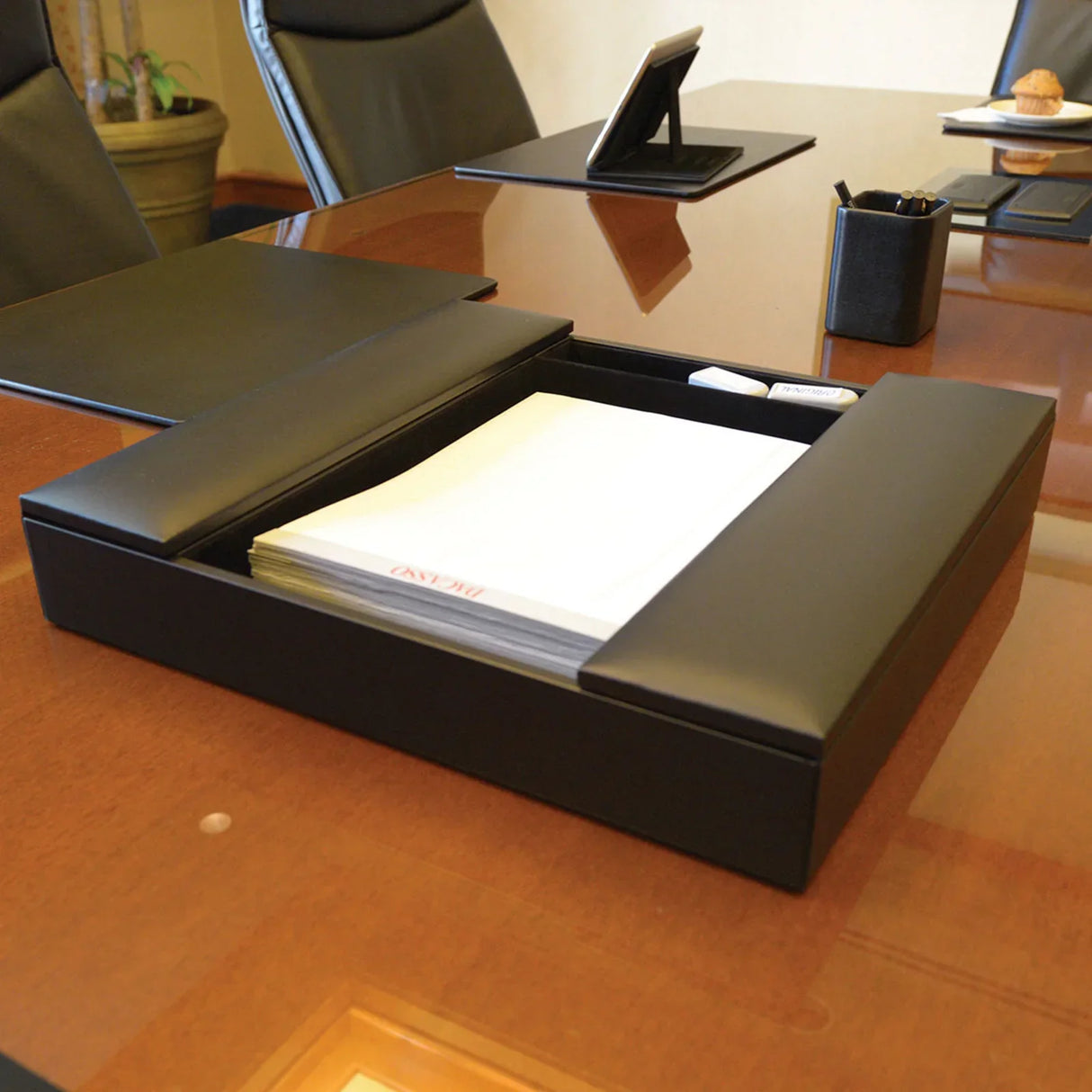 Black leather conference room organizer with notepad and accessories on meeting table