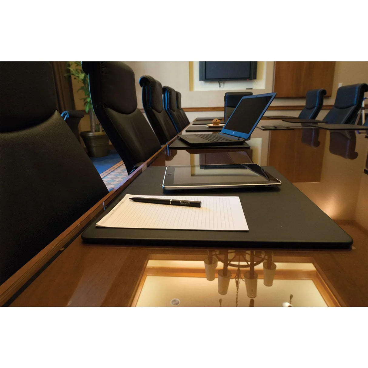 Black leatherette conference table pad on meeting table with notepad, pen, and laptop