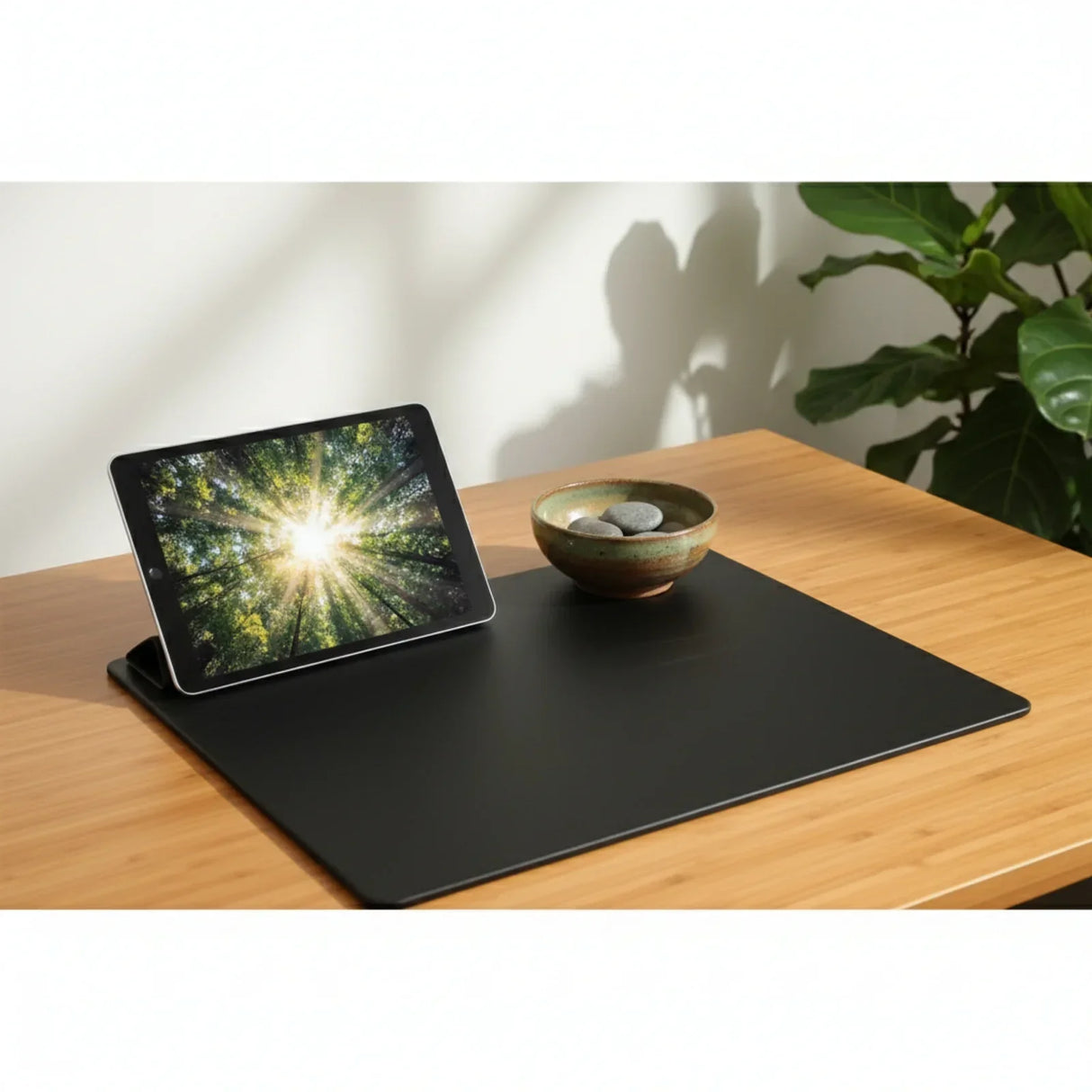 Black leatherette conference table pad on wooden desk with tablet and bowl of stones
