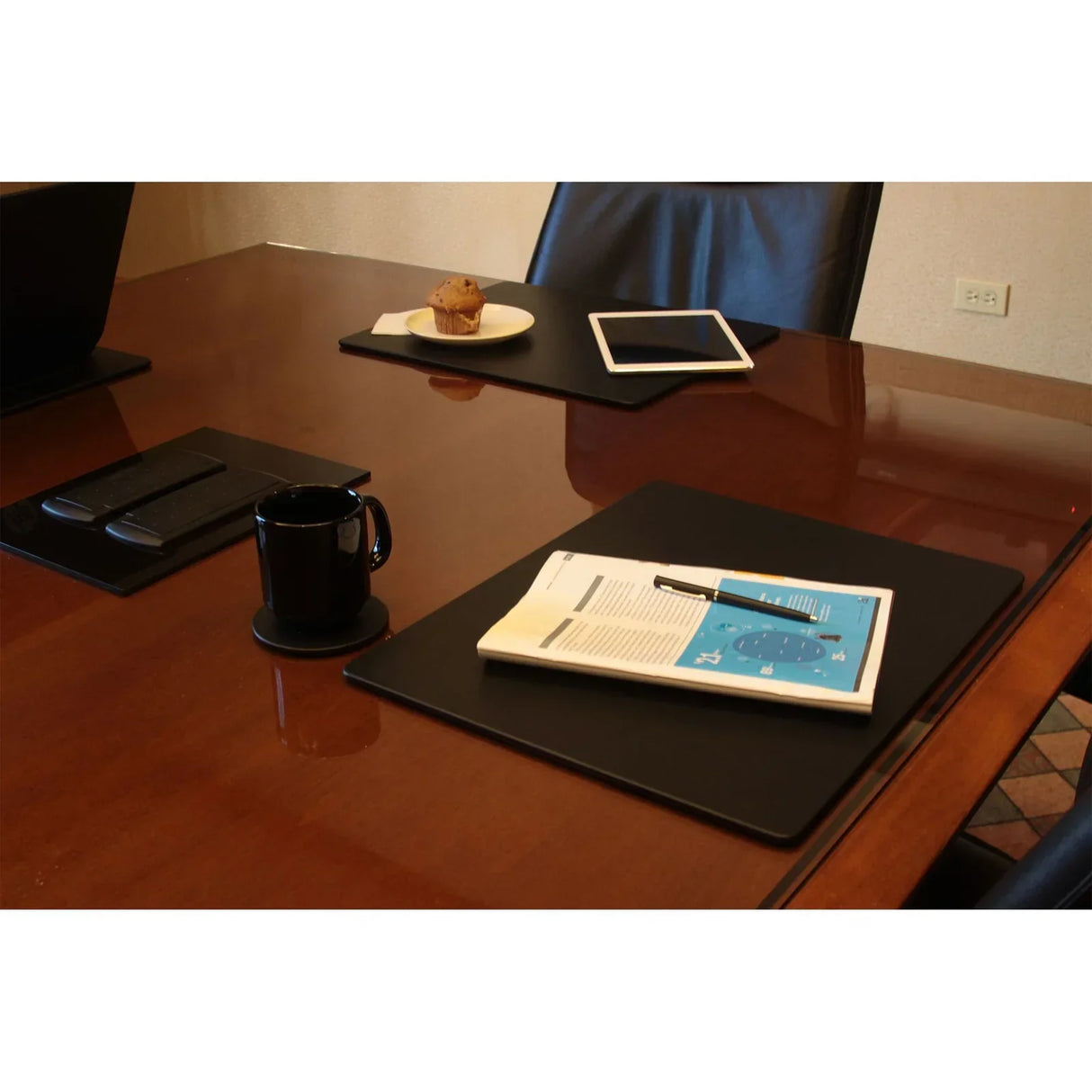 Black leatherette conference table pads on a meeting table with office supplies