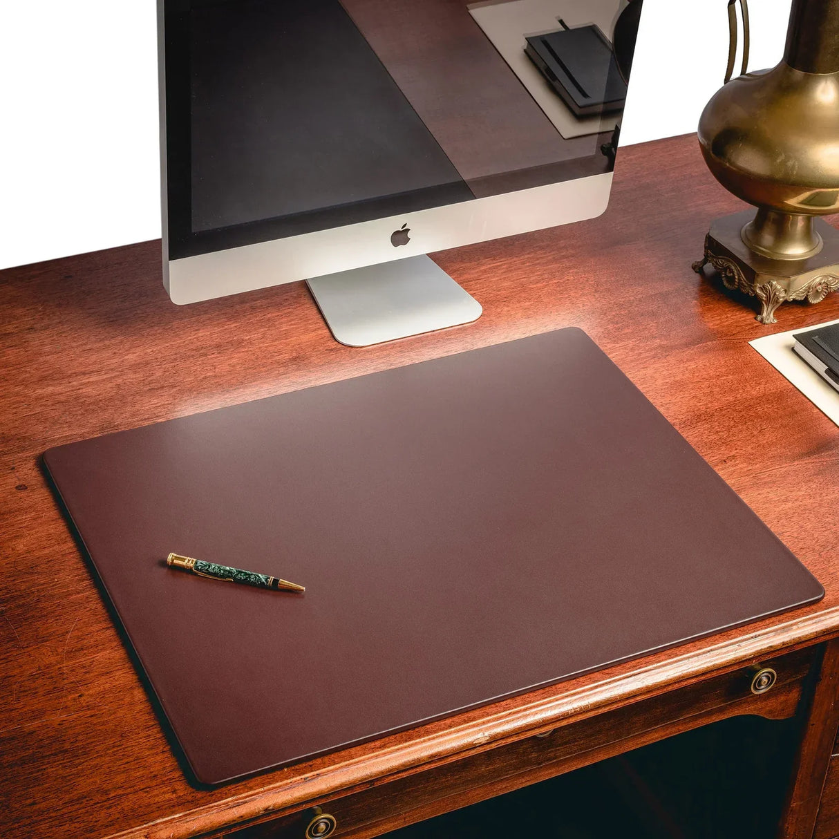 Chocolate brown leather desk mat on a wooden office desk with computer and pen
