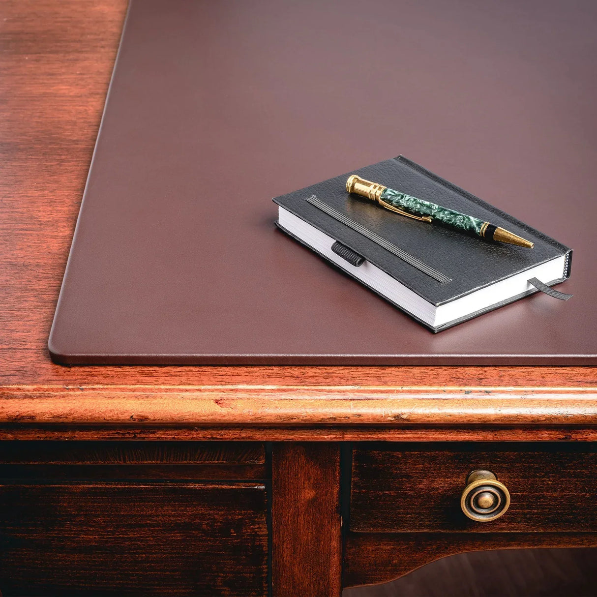 Chocolate brown leather desk mat on wooden desk with notebook and pen