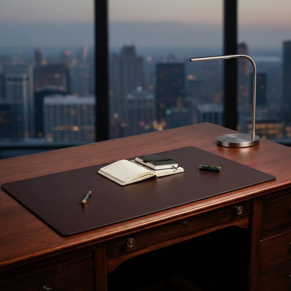 Chocolate brown leather desk mat on wooden desk with notebooks, pens, and modern lamp.