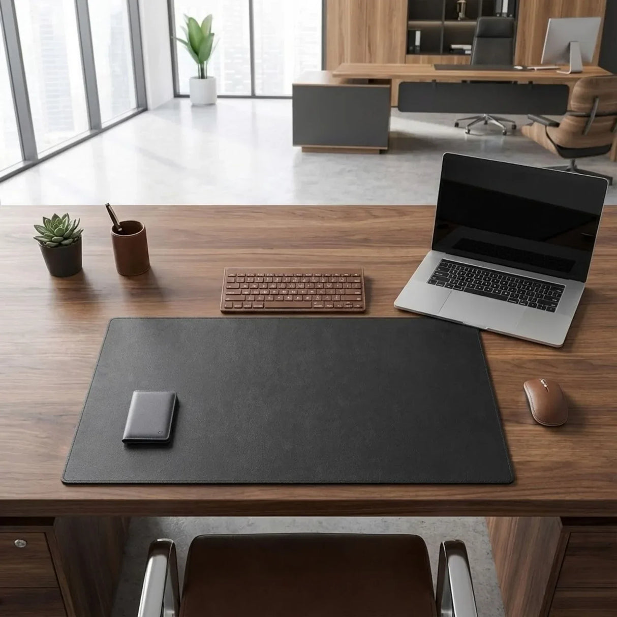 Black leather desk mat on modern office desk with laptop, keyboard, mouse, wallet, and plant