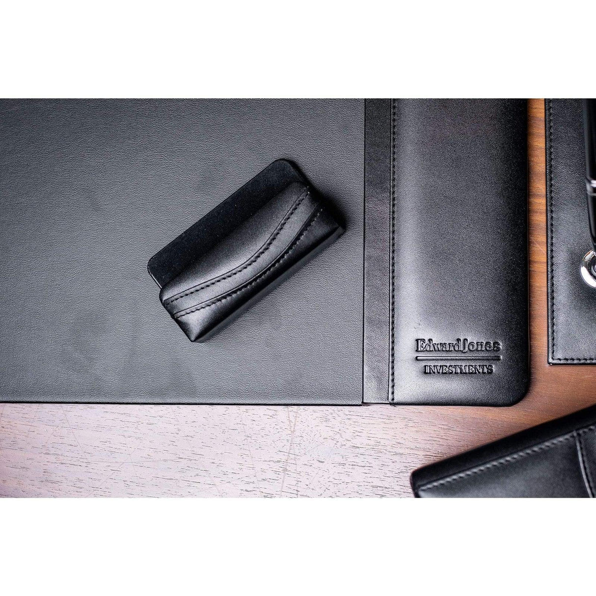 Black leather business card holder on office desk with matching leather accessories