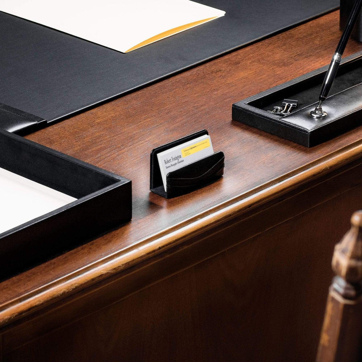 Black leather business card holder on an organized wood office desk