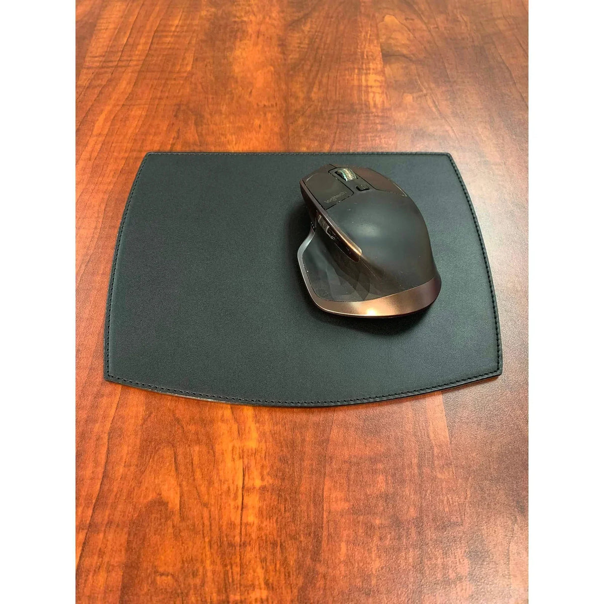 Black leather mouse pad with ergonomic mouse on wooden desk