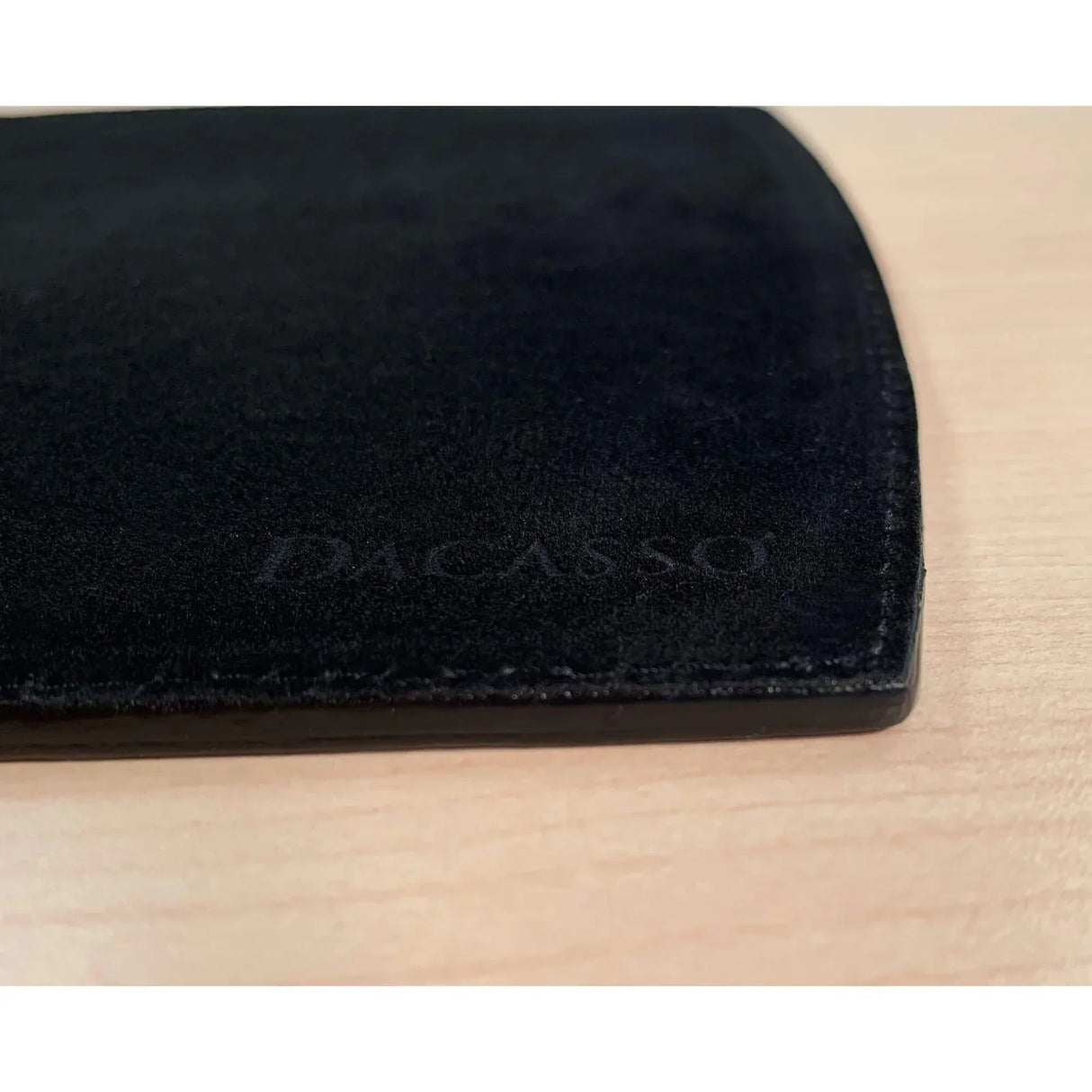 Black leather mouse pad with stitched edges on a light wood desk surface