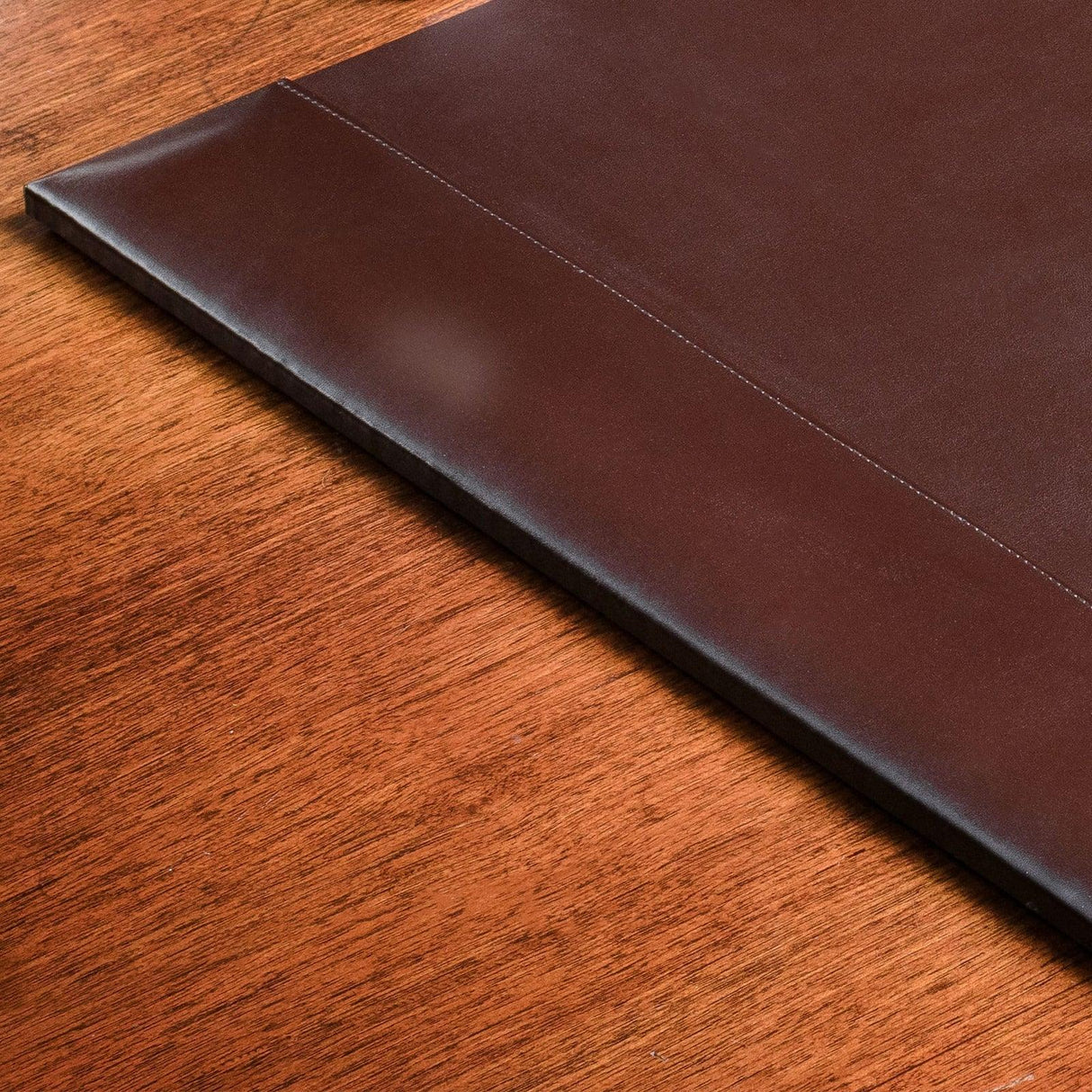Dark brown bonded leather desk pad on wooden desktop