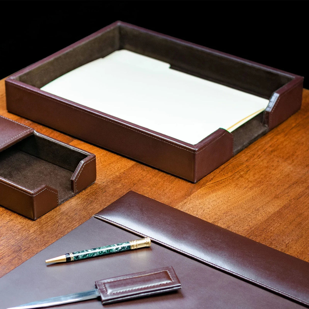 Dark brown bonded leather letter tray on wooden desk with matching office accessories