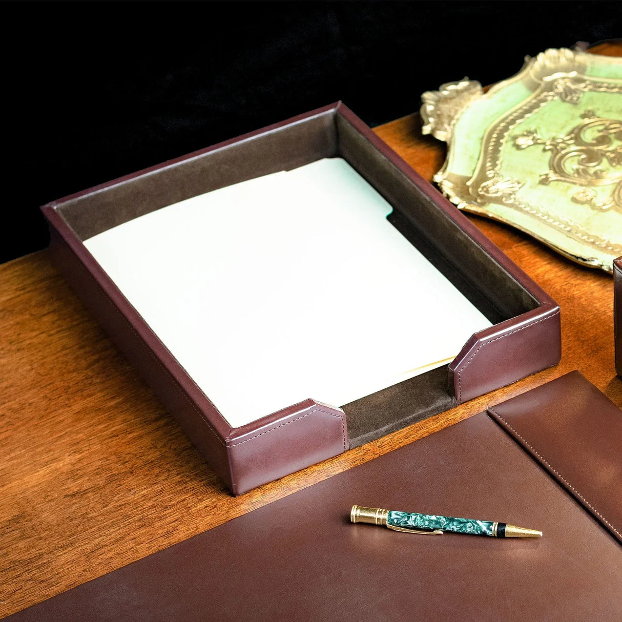 Dark brown leather letter tray with papers on a wooden office desk, elegant workspace accessory
